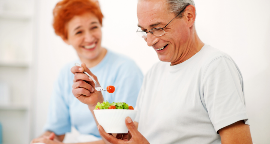 senior woman watching her husband eat a health salad