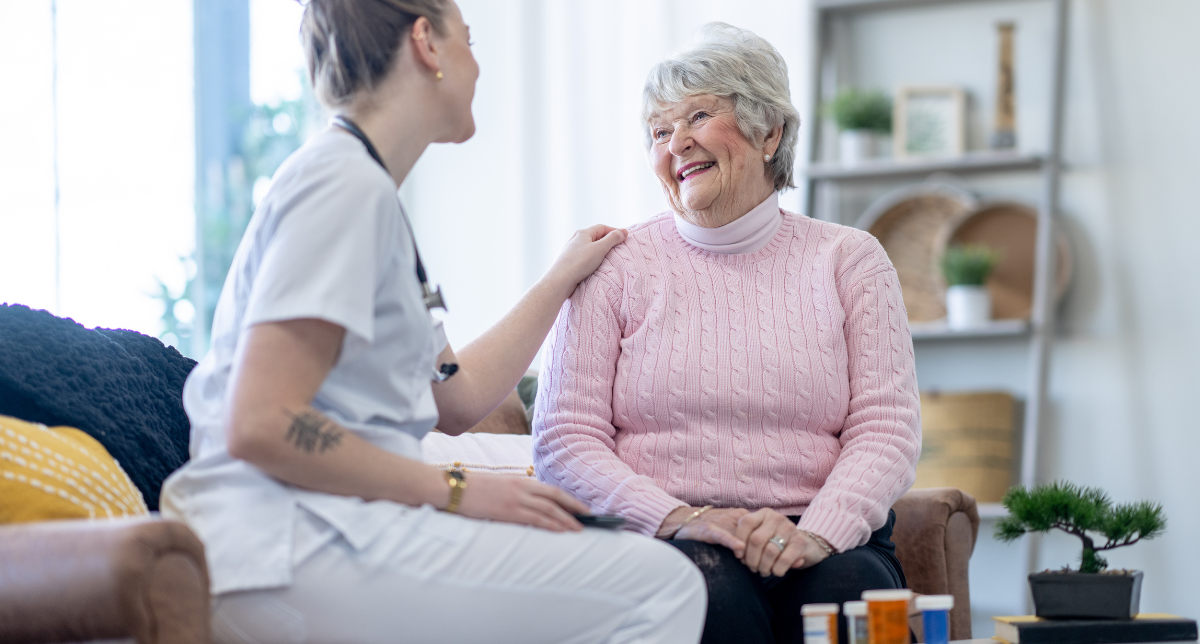 caregiver resting her hand on senior woman's shoulder while talking with her