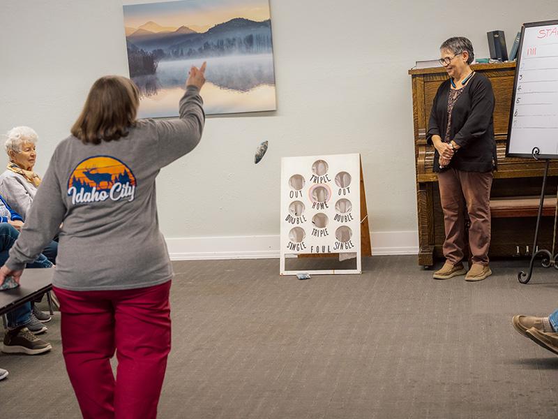 senior woman throwing bingbag into a game board