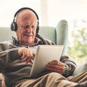 An older man talks to a loved one on a tablet.