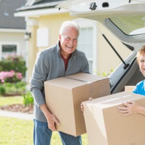 Two older adults carry boxes as they prepare to downsize.